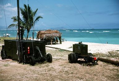 A mobile communications van and an MB-19 generator set stand on the beach during inshore undersea warfare operations