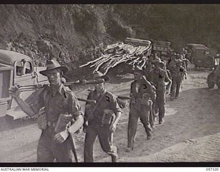 Troops of the 2/12th Battalion passing vehicles held up at the Rouna Traffic Control Post No. 2 because of blasting further along the road. Shown: QX37542 Corporal N L Dawson (1); QX47526 Private ..