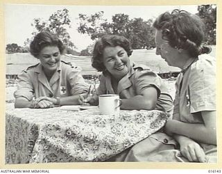 1943-11-17. NEW GUINEA. AUSTRALIAN ARMY MEDICAL WOMEN'S SERVICE (AAMWS) HAVE AFTERNOON TEA IN THE OUTDOORS. LEFT TO RIGHT - CORPORAL (CPL) M. MUNRO OF CAULFIELD, VIC., LANCE CORPORAL L. EVANS OF ..