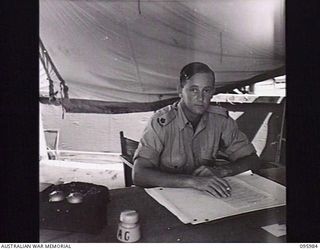 CAPE WOM, WEWAK AREA, NEW GUINEA. 1945-09-01. MAJOR D.S.I. BURROWS, DEPUTY ASSISTANT ADJUTANT GENERAL, HEADQUARTERS 6 DIVISION AT HIS DESK