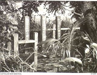 MADANG, NEW GUINEA. 1944-04-25. AN AUSTRALIAN SOLDIER STANDS BESIDE THE GRAVES OF THREE JAPANESE OFFICERS SITUATED 200 YARDS FROM THE PIER ALONG THE MADANG ROAD