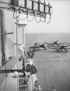 AT SEA OFF RABAUL, NEW BRITAIN. 1945-09-06. THE FLIGHT DECK OF THE AIRCRAFT CARRIER HMS GLORY WITH CORSAIR AIRCRAFT AND CREW ON STERN AND THE RN SLOOP, HMS AMETHYST IN ITS WAKE. THEY ARE PREPARING ..