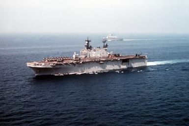 A port bow view of amphibious assault ship USS SAIPAN (LHA 2) underway during the NATO Southern Region exercise DRAGON HAMMER '90. In the background is the British light aircraft carrier HMS INVINCIBLE (R-05)