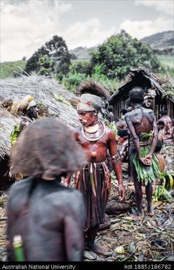 Mendi men standing outside of buildings