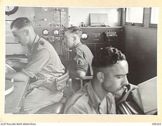 WEWAK, NEW GUINEA. 1945-10-29. MEMBERS OF 1 BROADCASTING STATION, AUSTRALIAN ARMY AMENITIES SERVICE WORKING AT RADIO STATION 9AJ DURING A BROADCAST. IDENTIFIED PERSONNEL ARE:- SERGEANT N.S. BRAY ..