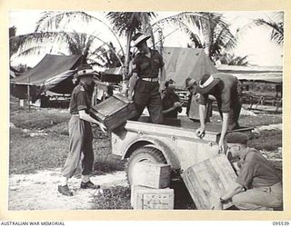 JACQUINOT BAY, NEW BRITAIN, 1945-08-25. MEMBERS OF NO. 2 MOBILE TEAM LAND HEADQUARTERS SCHOOL OF ARMY EDUCATION PREPARING TO LEAVE THIS AREA FOR BOUGAINVILLE. SHOWN, LOADING BOXES ON A JEEP TRAILER