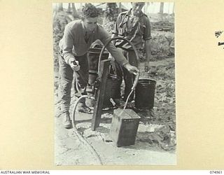 HANSA BAY, NEW GUINEA. 1944-07-29. NX136046 PRIVATE J.H. PONCHARD (1) AND NX156788 PRIVATE L.P. KERSHAW (2) OF THE 30TH INFANTRY BATTALION USING A CAPTURED JAPANESE PUMP TO DRAW WATER FROM A WELL ..