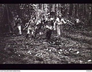 DREGER HARBOUR, NEW GUINEA. 1943-11-02. TROOPS OF THE 808TH UNITED STATES ENGINEER AVIATION BATTALION MOVING OUT THROUGH THE MUD TO WORK ON THE NEW AIRSTRIP. THEY ARE: T/5 L. AUXIER (1); PRIVATE ..