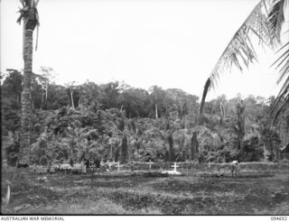 TOL AREA, NEW BRITAIN. 1945-08-01. NATIVES AND TROOPS AT WORK IN TOL CEMETERY. MEMBERS OF 2/22ND INFANTRY BATTALION WHO WERE MASSACRED BY THE JAPANESE IN THE TOL PLANTATION ACTION ARE BURIED HERE. ..