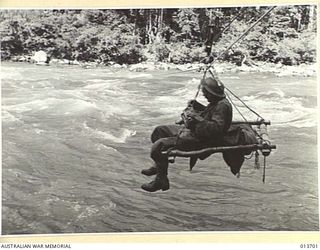 1942-12-01. NEW GUINEA. KANUSI. AUSTRALIAN TROOPS CROSS THE KANUSI RIVER ON FLYING FOXES HASTILY CONSTRUCTED BY ENGINEERS. (NEGATIVE BY G. SILK)
