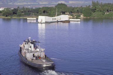 The large harbor tug NEODESHA (YTB-815) approaches the USS ARIZONA (BB-39) Memorial