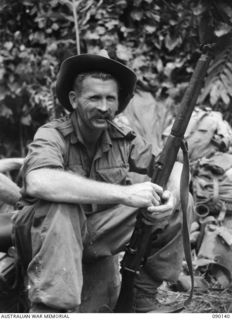 DAGUA, NEW GUINEA. 1945-03-27. PTE J.C. PLATER, 2/2 INFANTRY BATTALION, A COMPANY HQ, TIRED, BUT STILL CHEERFUL, SITTING ON A BOX