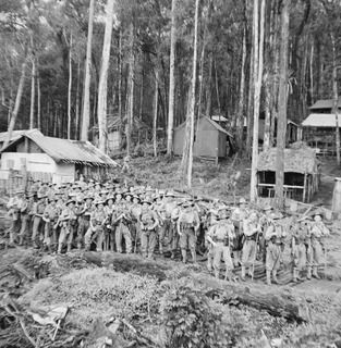 SKINDEWAI, NEW GUINEA, 1943-08-13. MEMBERS OF "A" COMPANY, 2/1ST AUSTRALIAN MACHINE GUN BATTALION AT THE STAGING CAMP, ON THEIR WAY TO THE FRONT LINE. SHOWN ARE:- NX25361 ACTING CORPORAL R. J. ..
