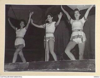 TOROKINA, BOUGAINVILLE. 1945-04-14. A SCENE FROM THE NUMBER "PALE MOON" PERFORMED BY THE BOB DYER CONCERT PARTY. THEY ARE ENTERTAINING TROOPS AT BOSELY FIELD. IDENTIFIED PERSONNEL ARE:- DOLLY MAC ..