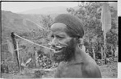 Older man with pierced nose, wears a cap netted from plant fibers