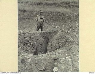 WANDOKAI, NEW GUINEA. 1944-04-17. SX10749 CAPTAIN W.R. MATES, 2/14TH FIELD REGIMENT, EXAMINING THE EFFECTS OF THE STATIC DETONATION OF A 4.2 INCH MORTAR BOMB ON A JAPANESE LOG BUNKER DURING TESTS ..