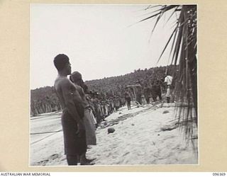 MUSCHU ISLAND, NEW GUINEA, 1945-09-09. OFFICERS OF AUSTRALIAN NEW GUINEA ADMINISTRATIVE UNIT, ATTACHED 6 DIVISION, AND THE FORMER JAPANESE NATIVE OVERSEER, INO, ADDRESSING A PARADE OF ISLAND ..