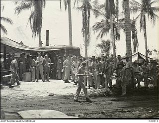MOMOTE, LOS NEGROS ISLAND, ADMIRALTY ISLANDS. C. 1944-03. GROUND CREWS OF NO. 79 (SPITFIRE) SQUADRON RAAF LINE UP FOR LUNCH AT THE MESS TENT UNDER COCONUT PALM TREES. THE MEN WERE EATING IN THE ..