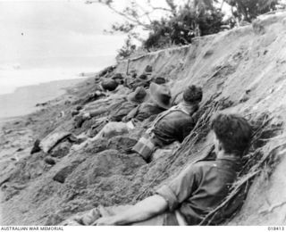 Aitape Sector, New Guinea. April 1945. Australian troops advancing along the northern New Guinea coast take shelter from Japanese shelling under a beach bank