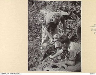 WEWAK AREA, NEW GUINEA. 1945-10-13. CRAFTSMAN I. PANNOWITZ (1) AND CORPORAL W. WRIGHT (2) MEMBERS OF 3 MOBILE TYRE WORKSHOP SECTION REMOVING A JAPANESE TYRE FROM ITS WHEEL