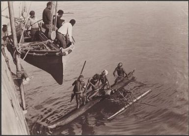 Southern Cross passengers being lowered in a lifeboat to trade with Santa Cruz people in canoes, Graciosa Bay, Solomon Islands, 1906 / J.W. Beattie