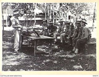 YALU, NEW GUINEA. 1945-08-03. SERGEANT WREN, NEW GUINEA TRAINING SCHOOL, INSTRUCTING STUDENTS IN THE METHOD OF STRIPPING A BREN LIGHT MACHINE GUN