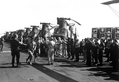 Colonel J. P. Faulkner, 22nd MAU commanding officer, and Captain J. M. Quarterman, USS GUAM (LPH 9) commanding offier, accept flags from the final runners as they cross the finish line during the GUAM`s "Run Across the Atlantic". The trans-Atlantic marathon began April 20th in Rota, Spain, and ended May 1st inside the 3-mile limit near Morehead City, North Carolina. A row of CH-46 Sea Knights are on the deck