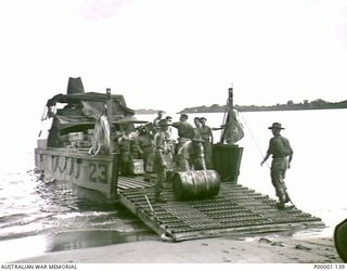 THE SOLOMON ISLANDS, 1945-05. AUSTRALIAN SERVICEMEN UNLOADING STORES FROM A BEACH LANDING CRAFT AT NORTH BOUGAINVILLE. (RNZAF OFFICIAL PHOTOGRAPH.)