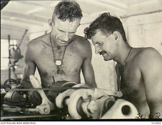 BOUGAINVILLE ISLAND, SOLOMON ISLANDS. 1945-01-12. 4664 SERGEANT J. W. LOVE, ADELAIDE, SA, IS INSPECTING MACHINE WORK PERFORMED ON THE LATHE BY 2573 CORPORAL G. C. HAMMOND, GLENELG, SA, IN THE ..