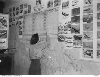 ST. LUCIA, QLD. 1943-11-24. VF346679 CORPORAL E. G. MASON OF THE GENERAL STAFF INTELLIGENCE, ADVANCED LAND HEADQUARTERS RECORDING THE FIGURES OF THE ENEMY AIRCRAFT IN THE NEW GUINEA AREA
