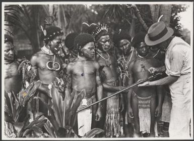 Frank Hurley explains his rifle to Amanen [?] villagers, Cape Nelson, Papua New Guinea, May 1921