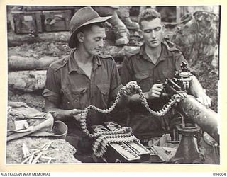 WEWAK AREA, NEW GUINEA, 1945-07-14. PTE A.R. MCGREGOR, (1) AND PTE W.P. DOYLE (2), MEMBERS OF HQ COMPANY, 2/8 INFANTRY BATTALION, CHECKING THE VICKERS AMMUNITION BELT READY FOR THE COVERING FIRE ..