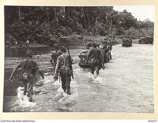 BOUGAINVILLE. 1945-05-20. TROOPS OF 24 INFANTRY BATTALION CROSSING HONGORAI RIVER AT MACKLIN'S CROSSING. THEY ARE PROTECTING JEEPS AND TRAILERS LOADED WITH AMMUNITION AND STORES FROM POSSIBLE ENEMY ..