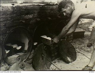 HANSA BAY, NEW GUINEA. 1944-07-29. NX87013 PRIVATE D.W. LYON, 30TH INFANTRY BATTALION FIELD BAKERY PLACING TINS OF BREAD IN THE UNIT OVENS