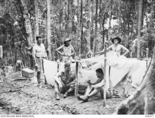 PAPUA, NEW GUINEA. 1942-08. SAPPERS OF THE 2/14TH AUSTRALIAN FIELD COMPANY, ROYAL AUSTRALIAN ENGINEERS, CAMP BESIDE THE ROAD THEY HAVE RECENTLY CONSTRUCTED THROUGH THE DENSE JUNGLE BETWEEN PORT ..