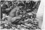 Larikeni of Furingudu measuring out kofu shell money to purchase packets of fish at market with sea people