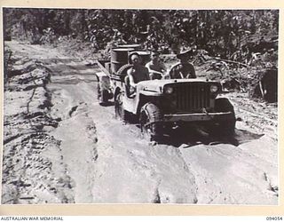 BOUGAINVILLE, 1945-07-16. A JEEP PULLING A TRAILER LOADED WITH 44-GALLON DRUMS FOR COLLECTING WATER FROM THE OGORATA RIVER, NEGOTIATING A MUDDY SECTION OF THE BUIN ROAD EAST OF THE RIVER. THE ..