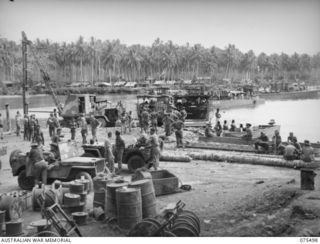 LAE, NEW GUINEA. 1944-08-27. THE BUSY EVERYDAY SCENE AT THE BEACH HEAD OF HEADQUARTERS, 5TH DIVISION. NOTE THE PILEDRIVER ON THE LEFT BEING USED TO BUILD A NEW JETTY FOR SMALL CRAFT