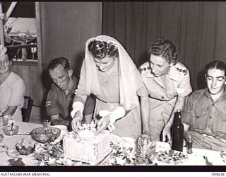 RABAUL, NEW BRITAIN, 1946-01-05. CORPORAL R. STANLEY, AUSTRALIAN MOVEMENT CONTROL, WATCHING HIS BRIDE, FORMERLY PRIVATE BARBARA JAMES, AUSTRALIAN ARMY MEDICAL WOMEN'S SERVICE (AAMWS), PREPARE TO ..