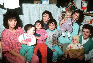 Mothers pose for a photograph with their children at Zbirni Refugee Camp during a visit by crew members of the amphibious assault ship USS GUAM (LPH-9). The sailors are visiting the camp during the Guam's port call in nearby Trieste, Italy