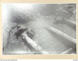 WEWAK AREA, NEW GUINEA, 1945-06-09. SAPPERS WORKING WITH 2/8 INFANTRY BATTALION, UP TO THEIR ARMPITS IN WATER, FIXING A CRIB JETTY BEFORE THEY PUT THE FINAL BRIDGE IN PLACE. BRIDGE BUILDING IS A ..