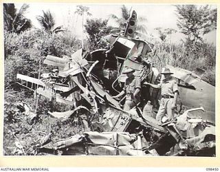 KAVIENG, NEW IRELAND. 1945-10-21. A SMASHED JAPANESE BOMBER IN ITS REVETMENT AT KAVIENG AIRSTRIP. AN AUSTRALIAN NEW GUINEA ADMINISTRATIVE UNIT ADMINISTRATIVE HEADQUARTERS IS BEING SET UP AT KAVIENG ..