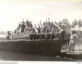 MADANG, NEW GUINEA. 1944-12-14. RAN PERSONNEL ABOARD THEIR LAUNCH, K9, CHEER LOUDLY AFTER RECEIVING THEIR AUSTRALIAN COMFORTS FUND CHRISTMAS PARCELS