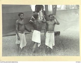 KOKODA, NEW GUINEA. 1944-04-13. NATIVES WORKING UNDER THE DIRECTION OF THE SUB DISTRICT OFFICE, AUSTRALIAN NEW GUINEA ADMINISTRATIVE UNIT, UNLOADING SUPPLIES FROM AN AIRCRAFT. ALL RATIONS ARE FLOWN ..