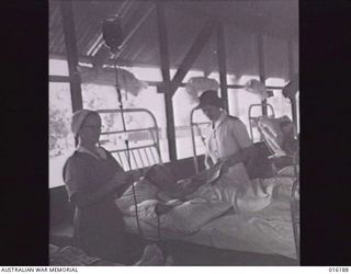NEW GUINEA. 1943-11-24. AT AN AUSTRALIAN FIELD HOSPITAL SISTER MCCAULEY WHO IS IN CHARGE OF THE BLOOD BANK, GIVES A TRANSFUSION TO PRIVATE D. HELLIWELL OF MAYO W.A., WARD SISTER LIEUTENANT F. ..