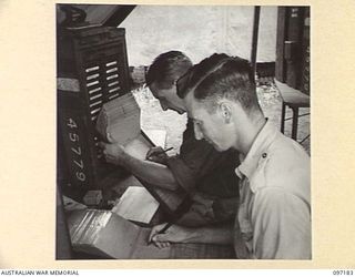CAPE WOM, NEW GUINEA. 1945-09-27. PRIVATE N. WESTBROOK (1) AND PRIVATE H.R. SKINNER (2), 110 BRIGADE ORDNANCE FIELD PARK, AT WORK IN THE UNIT ORDERLY ROOM