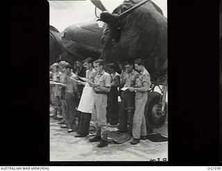 KIRIWINA, TROBRIAND ISLANDS, PAPUA. C. 1944-04. SERVICING CREWS OF NO. 30 (BEAUFIGHTER) SQUADRON RAAF INCLUDING A COOK (WITH APRON) SINGING HYMNS AT AN EASTER SUNDAY CHURCH SERVICE. THEY ARE ..