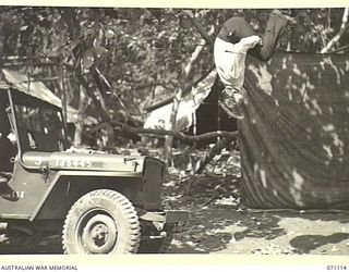 KILIGIA, NEW GUINEA, 1944-03-15. NX152367 CORPORAL C. MORGAN, ACROBAT AND COMEDIAN WITH THE 3RD ARMOURED DIVISION CONCERT PARTY, REHEARSING A BACK SOMERSAULT FROM THE BONNET OF A JEEP