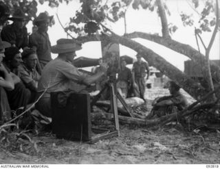 SORAKEN AREA, BOUGAINVILLE. 1945-06-07. LIEUTENANT H. ABBOTT, OFFICIAL WAR ARTIST, MILITARY HISTORY SECTION (1), WORKING ON A PAINTING OF A BARGE LANDING POINT ON LALUM BEACH. HE IS WATCHED BY ..