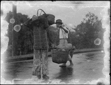 Two unidentified men carrying baskets at a market, Fiji